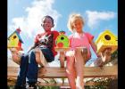 Atop a pergola in the Nance Elementary Reading Garden, Damarian Bailey, left, and Sydnee Pugh sit between some of the birdhouses made by students. CDN| Robert S. Bryan Article Image Alt Text