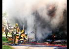 Chief Forrest Valentine, at left, rounds the corner as D.J. Woodall and Mark Switzer work on extinguishing the flames Wednesday at this home on S. 12th Street.